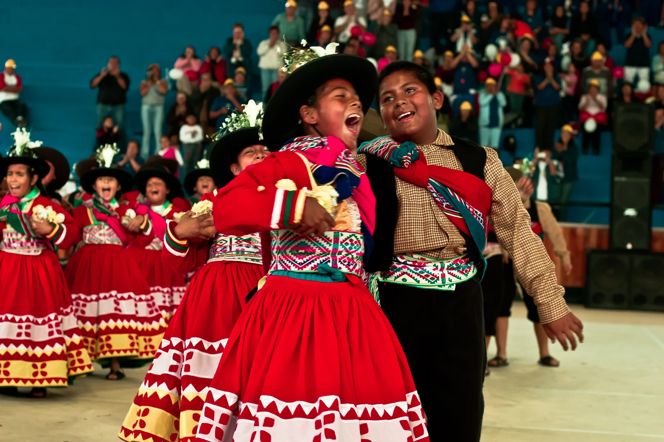 Two dancers in bright embroidered clothing laugh together