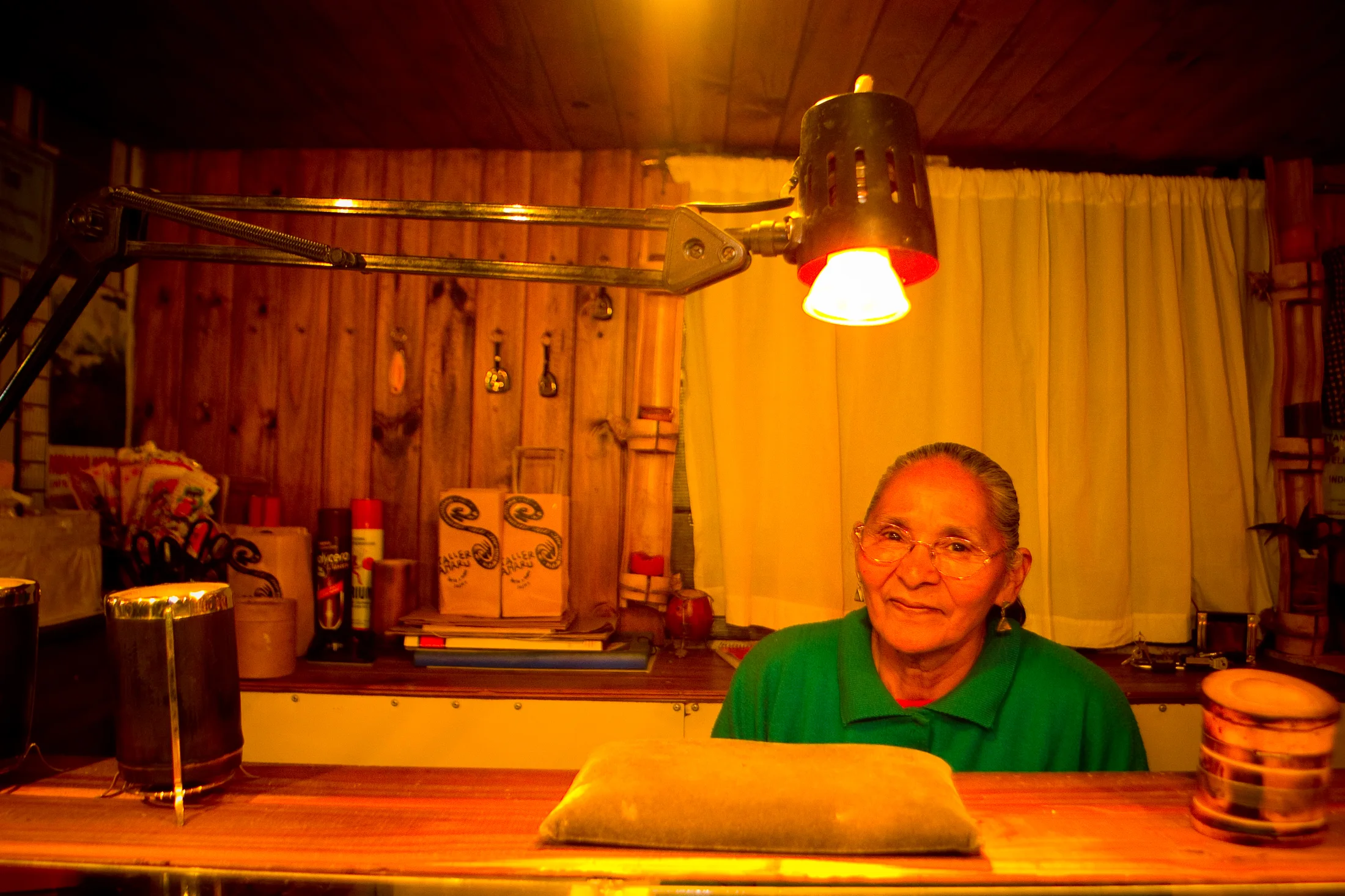 An older craft seller sitting among clay pottery at night
