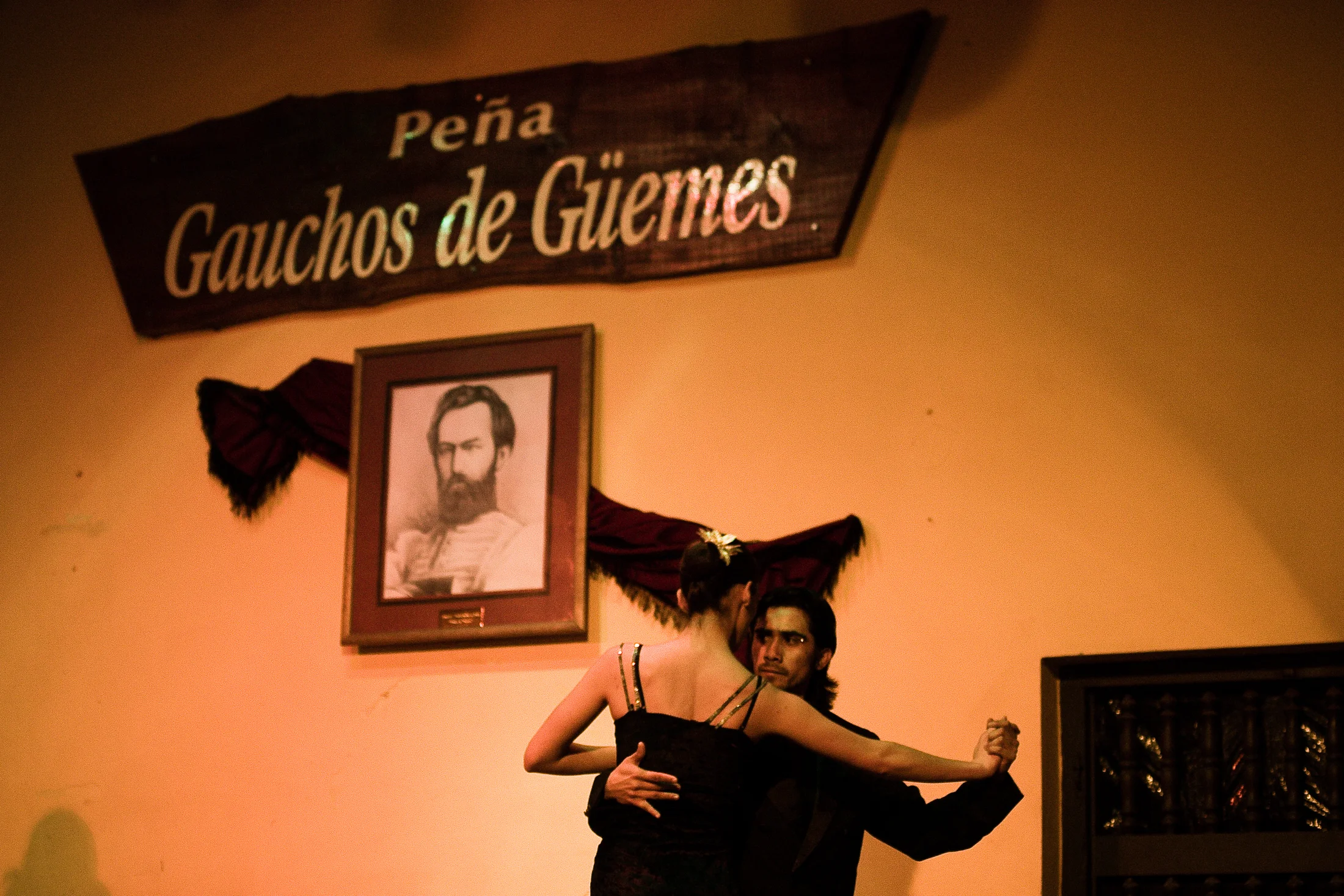 Folkloric dancers perform beneath the sign Peña Gauchos de Güemes